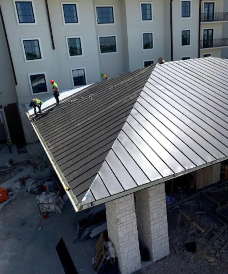 Crew installing standing seam metal roof panels on a commercial project in North Adams